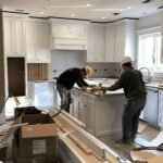 Construction Workers Installing New Cabinets and Appliances During a Full Kitchen Renovation